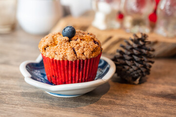Homemade baked blueberry muffin with pine cone on wooden table