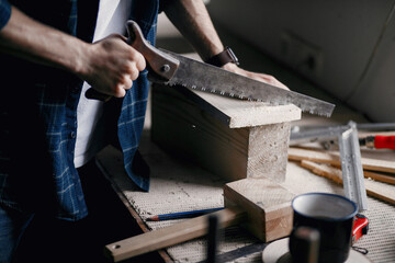 Craftsman cutting a wooden plank. Worker with wood. Man in a blue shirt.