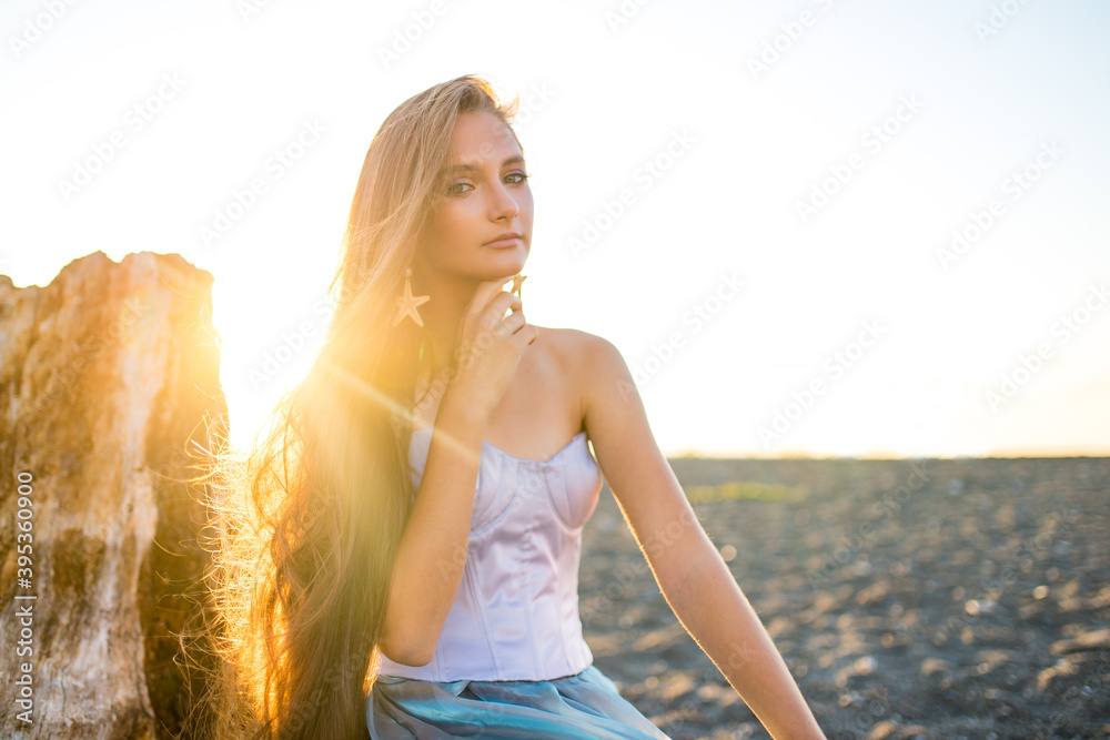 Wall mural mermaid myth in sunset on beach shore with fish star shells pearls earrings jewelry