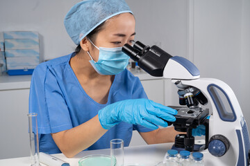 Femme asiatique dans un laboratoire de recherche médicale avec microscope.