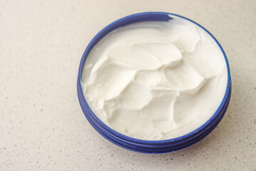 Open blue container with white cream on a marble table.
