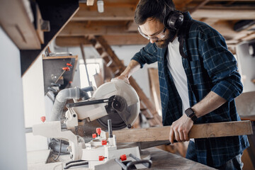 Wood cutting with circular saw. Closeup of mature man sawing lumber.