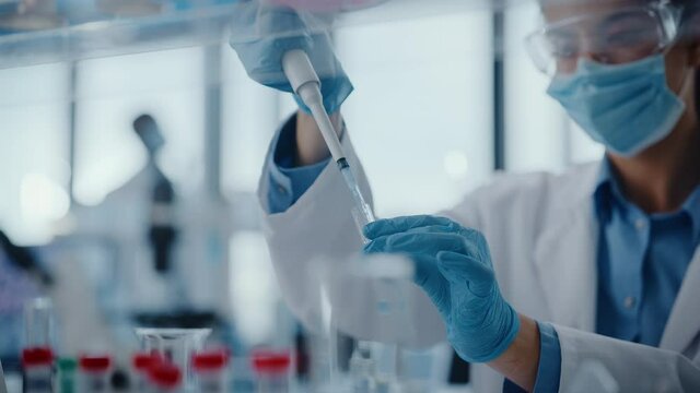 Medical Research Laboratory: Portrait of a Female Scientist Wearing Face Mask Using Micro Pipette for Analysis. Advanced Scientific Lab for Medicine, Biotechnology Development. Close-up Shot