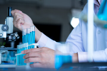 hands of  Asian man medical scientist testing test tube in clinical laboratory with microscope. 