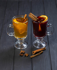 Two glasses of red and white mulled wine on black wooden background
