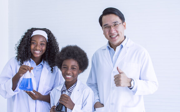 Portrait Of Asian Male Teacher And African Black  Students Studying Science In Classroom