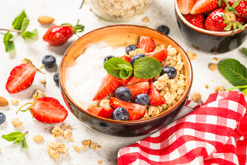 Greek yogurt granola with fresh berries on white stone table. Close up.