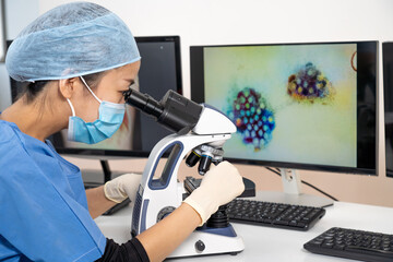 Femme médecin asiatique regarde au microscope des images médicales du covid-19 et de scanner des poumons infectés.