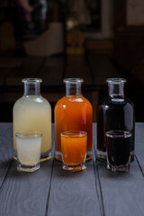 Assorted alcoholic cordials in glasses and decanters on dark wood background