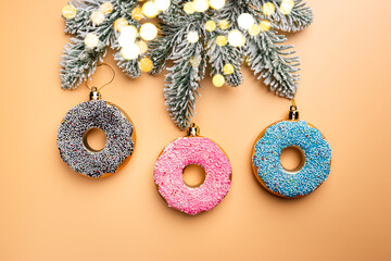 Christmas banner with toy glazed donut with sugar sprinkling and fir tree branch, top view. Orange pastel background.