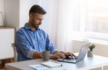 Fototapeta premium Unemployed man scrolling job search website at home using laptop computer