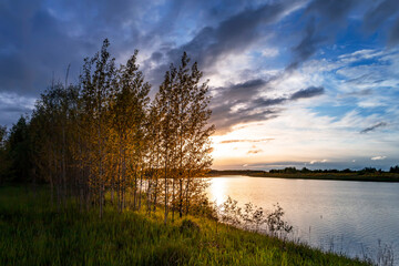 Beautiful summer sunset on the lake. Mystic clouds on sky.
