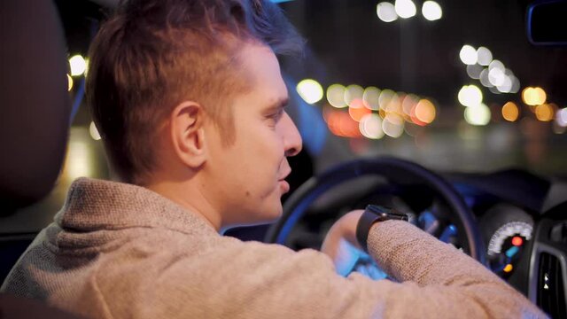 Happy driver using smartwatch in a car for handsfree voice recorder recognition audio message command late night. creative man with smartwatch using voice command recorder