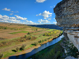 Fototapeta na wymiar Beautiful landsaft of rocky hills that is crossed by a meandering river. Sunny day with blue sky with white clouds. Raut River, Old Orhei, Moldova.