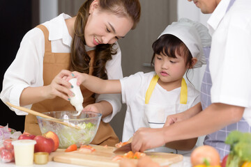 Asian parents are teaching their daughters to easy home cook salad foods. Family enjoys cooking together home cook in kitchen room at modern home. Focusing on center girl children.