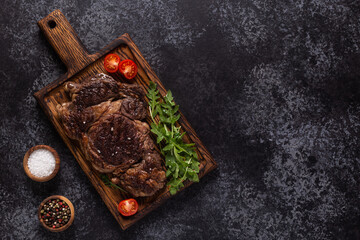 Grilled beef steak with spices on a wooden board.