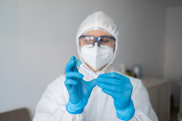 Medicine woman wearing protective gear, holding a test tube for 2019-nCoV analyzing. Coronavirus blood test concept. Selective focus