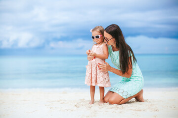 Adorable little girl and young mother on tropical white beach