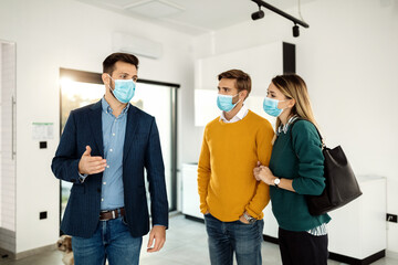 Real estate agent talking to a couple while showing them a new apartment during coronavirus pandemic.