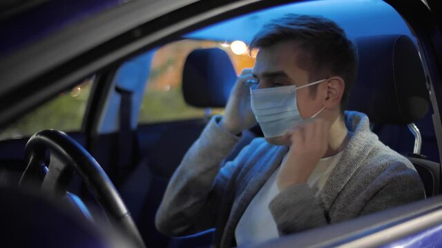 Happy businessman or taxi driver putting on medical face mask to prevent covid or coranavirus quarantine pandemic. Freelancer in a car after school in a face mask due to covid-19. Delivery service.