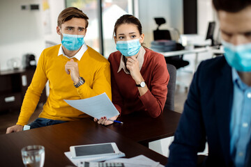 Distraught couple analyzing paperwork while having a meeting with bank manager during coronavirus pandemic.