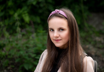 Naklejka premium Beautiful and smiling girl on a background of green grass. Portrait of a girl with long hair