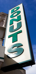 Low angle view of DONUTS sign against blue sky.