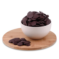 Candy dark chocolate drops in white ceramic bowl on wood board isolated on white background, copy space.