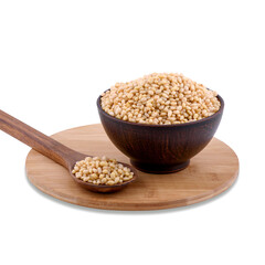 Pine nuts in brown bowl and spoon on wood board isolated on white background, copy space.