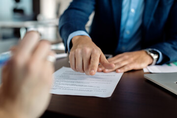 Close-up of financial advisor pointing at place of signature on a contract.