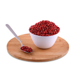 Pink pepper peas in white bowl and spoon on wood board isolated on white background, copy space.