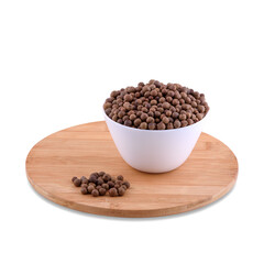 Allspice in white bowl on wood board isolated on white background, copy space.