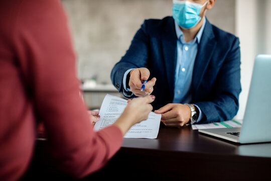 Close-up Of Real Estate Agent Signing An Agreement With A Client.