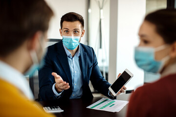 Financial consultant talking to clients while using digital tablet during a meeting.