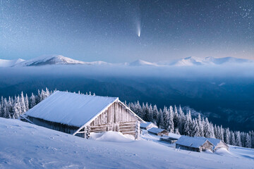 Fantastic winter landscape with wooden house in snowy mountains. Starry sky with comet and snow covered hut. Christmas holiday and winter vacations concept