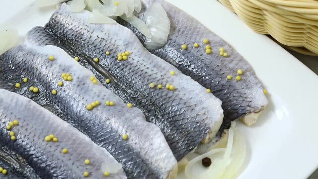 Traditional Dutch sour herring with onions and mustard seed close up