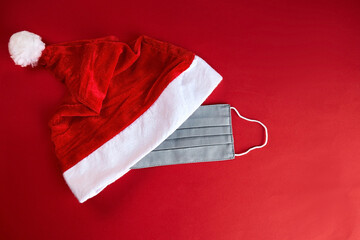Santa Claus hat with face mask on a red background. Coronavirus Christmas