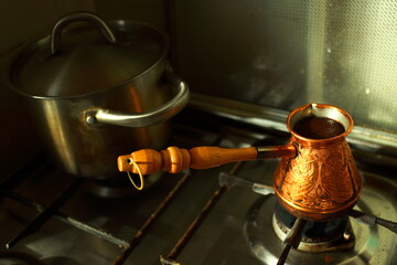 Closeup of brass cezve full of hot coffee on the stove
