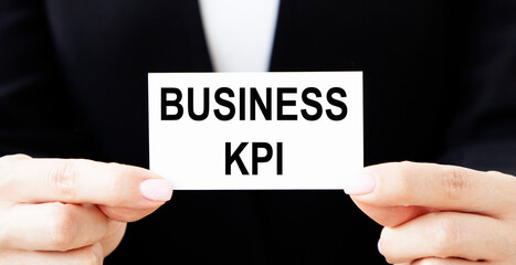 A businessman holds a business card with the business KPI text in front of him.