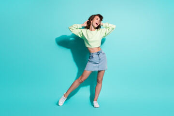 Fototapeta na wymiar Full length body size photo of cheerful fit girl laughing smiling with closed eyes touching hair isolated on vibrant teal color background