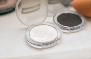 Round powder box with shadows, cosmetics stands on a white background