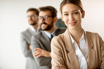 Smiling young business woman standing with group of corporate colleagues in a row together