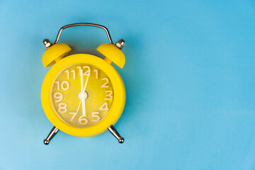 Yellow alarm clock close-up on a blue background. It's Blue Monday time.