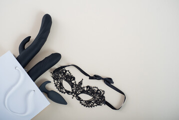 A set of purchases in a sex shop. Top view of dildo anal plug and mask in paper bag on white...