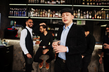 Stylish arab man against group of handsome retro well-dressed guys gangsters spend time at club, drinking on bar counter. Multiethnic male bachelor mafia party in restaurant.