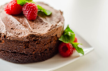 Gluten free tasty round cake based on Belgian chocolate decorated with fresh raspberries and mint