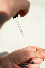 Close-up of a pipette with pink skin care serum.Macro photo of a drop of oil, skin care products.Cosmetology and skin care concept