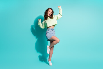 Photo of young yelling woman celebrate victory wear green sweater jeans skirt isolated on turquoise color background