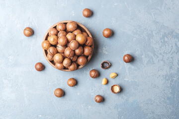 Bowl of macadamia nuts on a blue concrete background. Top view.