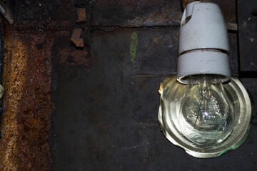 Light bulb on the background of old rusty iron, reflector cover from the can.